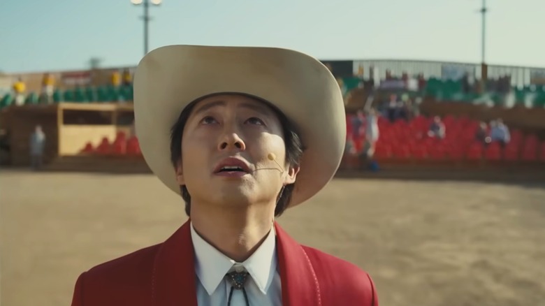 Steven Yeun as Ricky Park looking up at a rodeo in Nope