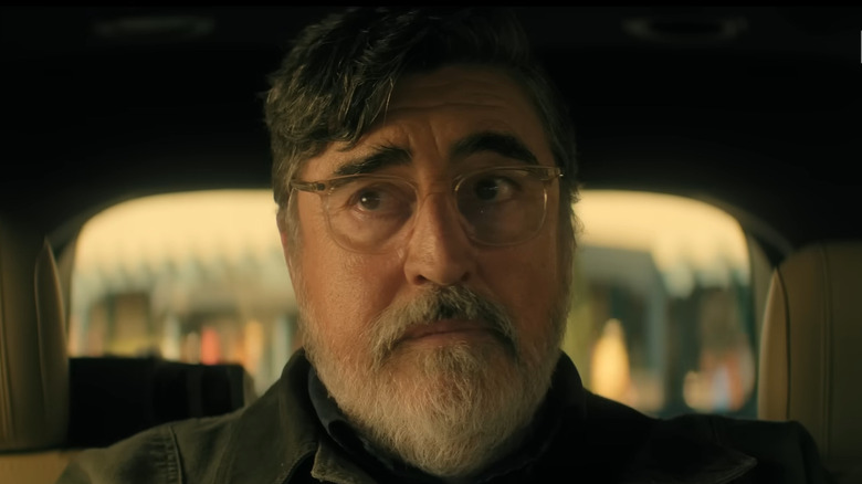Alfred Molina as Sam Cooper inside a car, looking concerned and confused