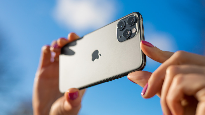 A person taking photo on an iPhone 11 Pro Max in bright outdoors