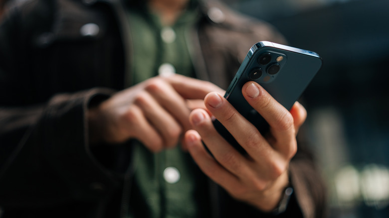 A man holding and using an iPhone