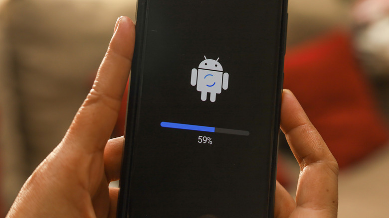 A user holding Android phone with software update in progress