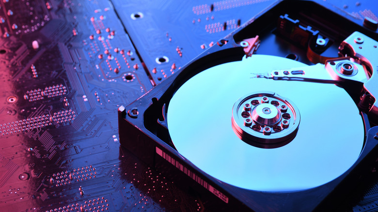 A hard disk drive on top of a computer component bathed in neon light