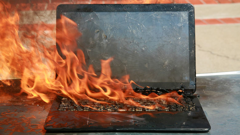 A laptop on fire with a shattered screen