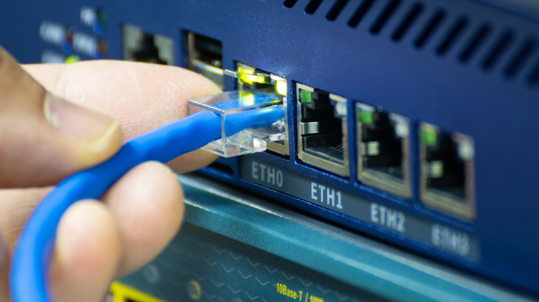 A person plugging an Ethernet cable in a modem