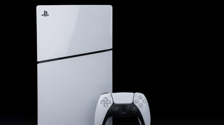 A PlayStation 5 console frontal view in a vertical position next to a DualSense controller