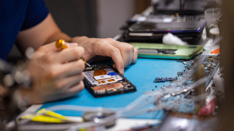 A technician repairing console components on a workbench