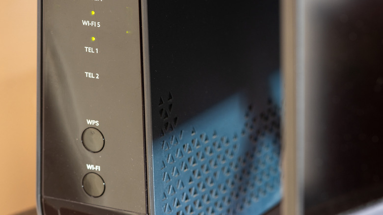 Black router with glowing lights and dedicated buttons for WPS and Wi-Fi