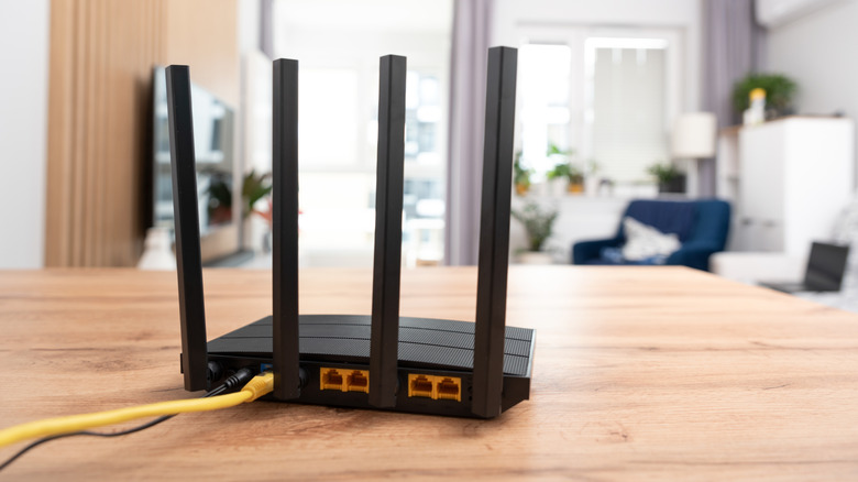 black wi-fi router with four antennas placed on a wooden table
