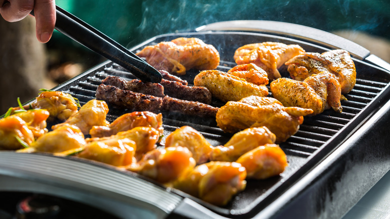 Electric grill with cevapcici and chicken wings