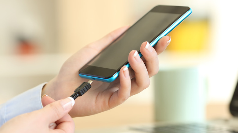 A person connecting a charging cable into a phone