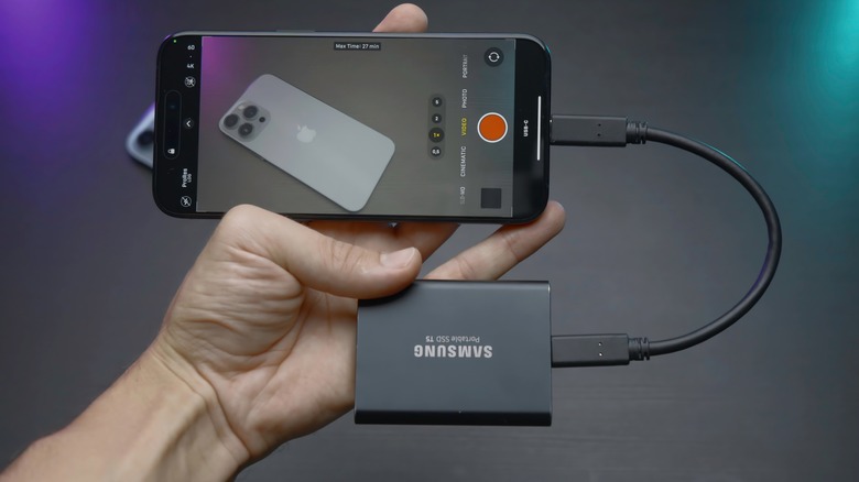 A phone connected to an external drive, recording an iPhone via camera app