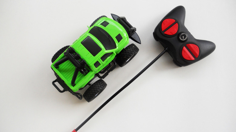 A remote control green toy car with its remote