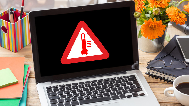 Laptop on a table showing a high temperature icon on the screen