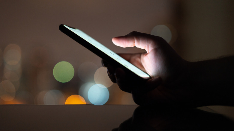 Bright smartphone display being viewed in a dark setting at night.