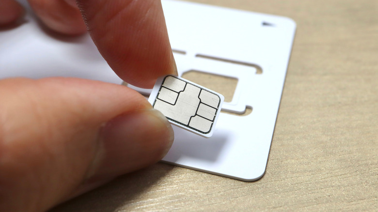Physical SIM card being taken out of its temporary frame.