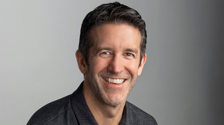Apple's future CEO, John Ternus, smiling in front of a gray background.