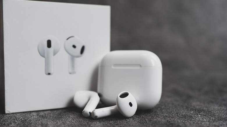 AirPods 4 earphones next to the charging case and retail box.