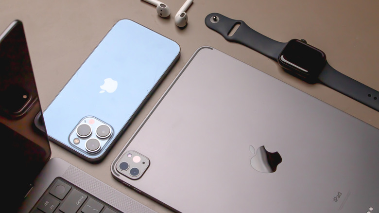 MacBook, iPhone, iPad, Apple Watch, and AirPods, on a table.