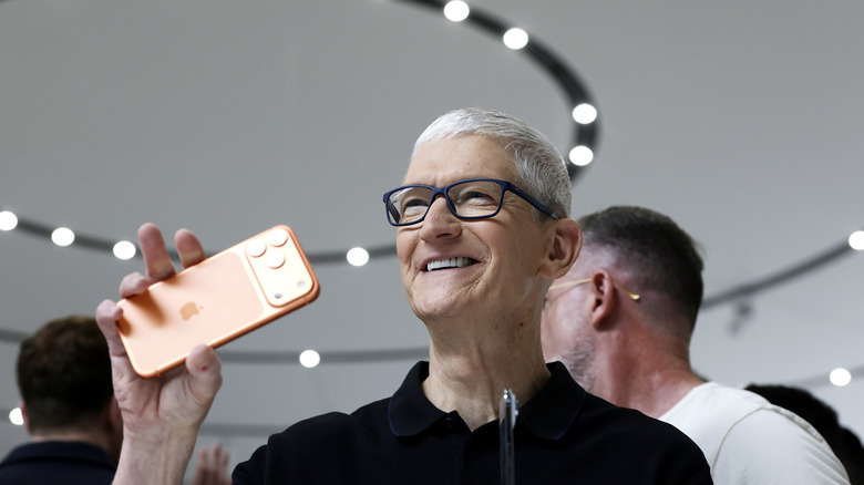 Apple CEO Tim Cook holding an iPhone and smiling