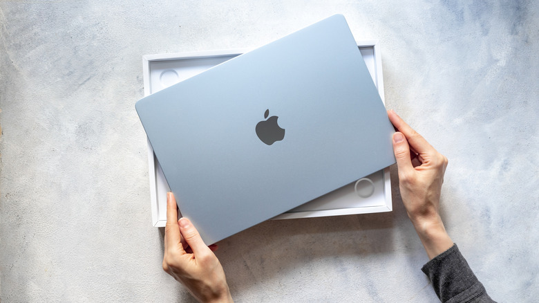 Person holding a MacBook out of the retail box.