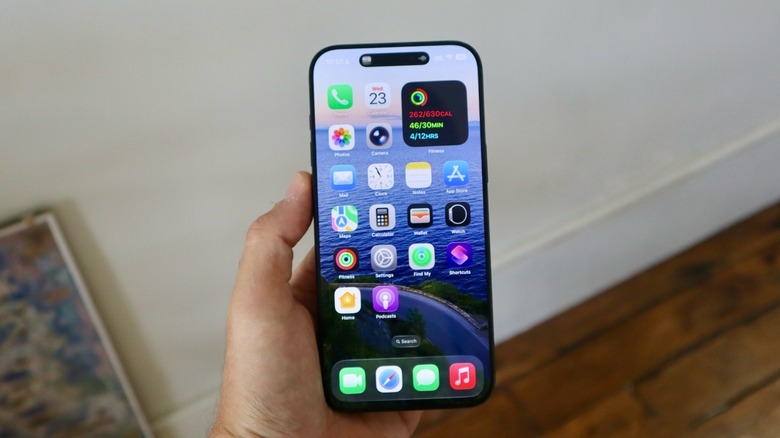 A hand holding an iPhone running iOS 26