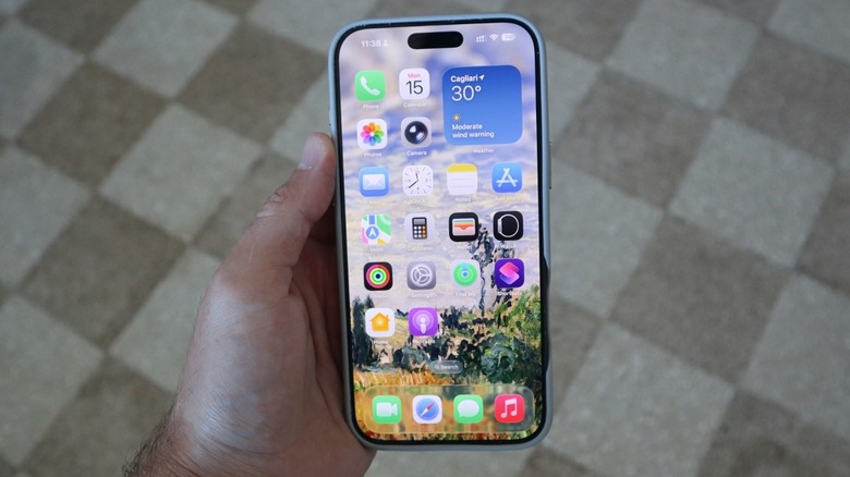 A hand holding an iPhone running iOS 26