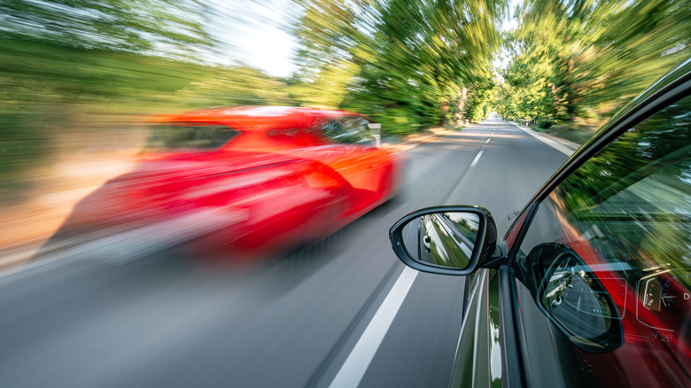 A card speeding by another on a road