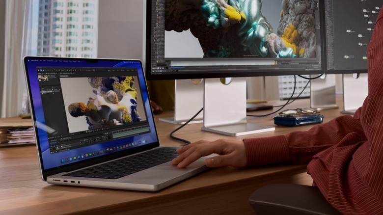 A woman working on a MacBook Pro with two connected Studio Displays