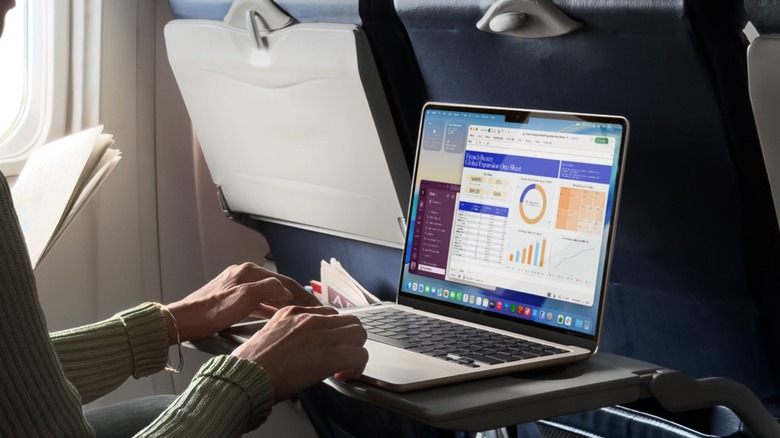 A person working on a MacBook Air in a plane