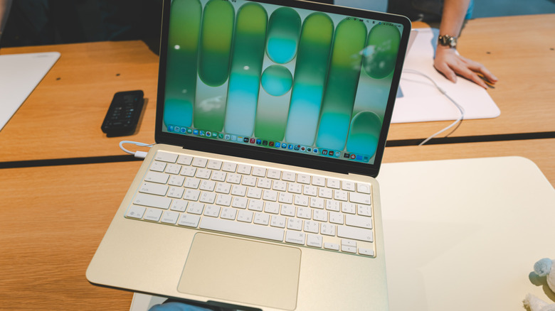 person holding macbook neo in an apple store