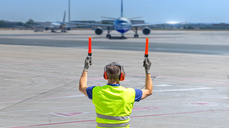 An air marshal directing a plane on an airport runway