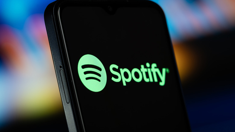 A cellphone displaying the Spotify logo against a blurred background