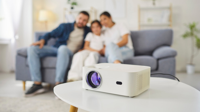 A projector placed in front of a family sitting on a couch