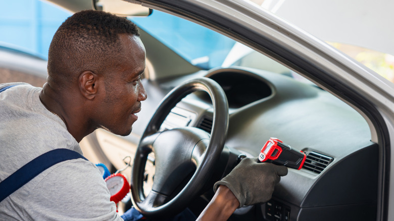 Man checking the temperature of a car's AC vent
