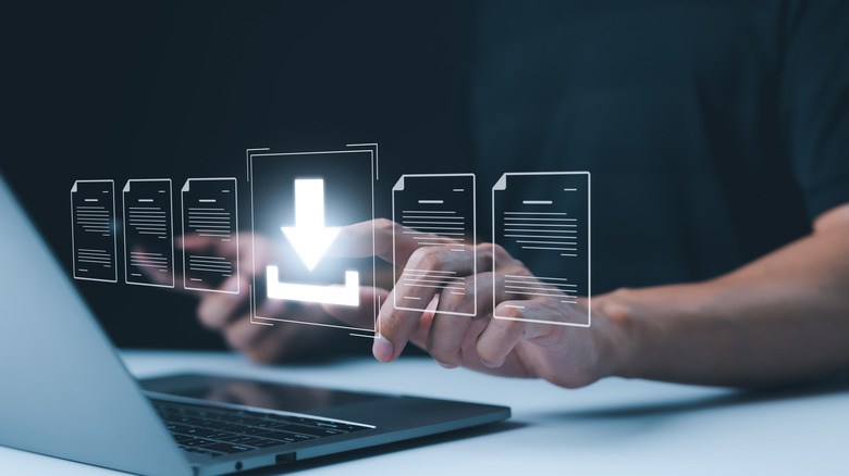 illustrated concept for downloading file hovering above laptop, man's hands visible in background