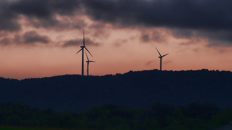 New York wind farm with cloudy sky and sunrise in background.