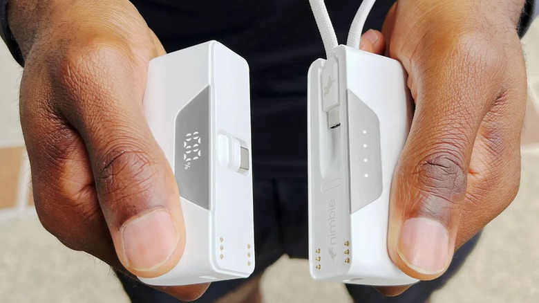 An individual holding both modules of a Nimble Sharepower Portable Charger in each of their hands, the device can be split into two halves for multiple charging options