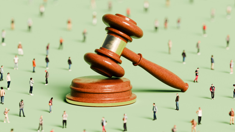 a legal gavel with small people around it, symbolic image