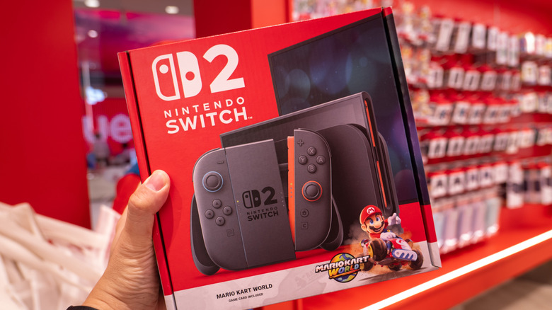 A person holding a Nintendo Switch 2 bundle box with Mario Kart World