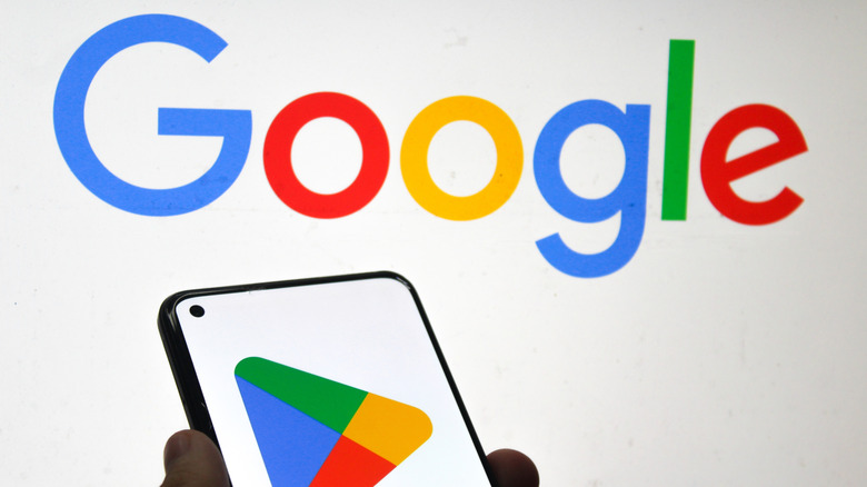 Google logo on background, smartphone in foreground with Play Store logo visible