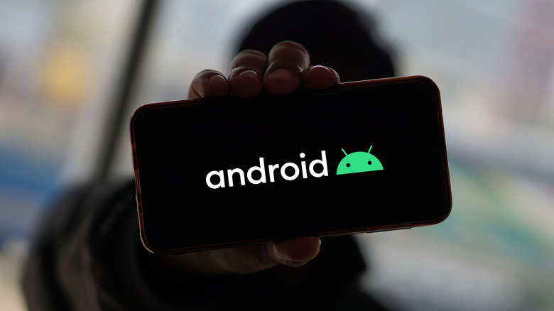 person holding a smartphone with Android logo on it