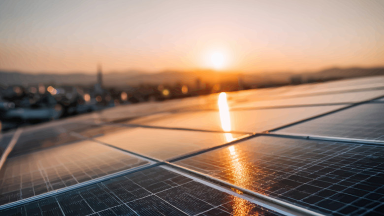 Solar panels on roof with sun in background