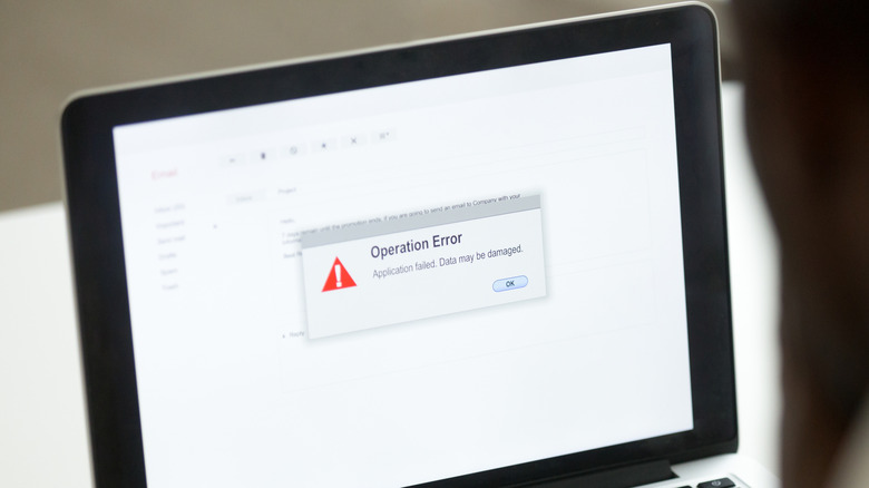 operation error showing on monitor of laptop, man looking at it out of focus