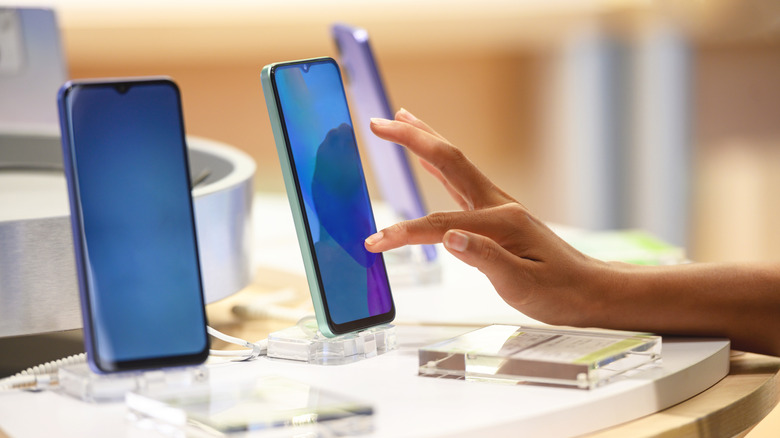 A person trying out different phones in a retail setting
