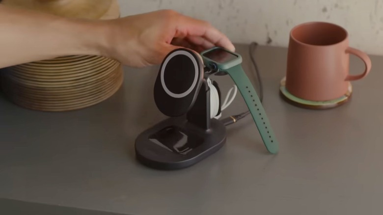 A hand placing a watch on an OtterBox charger