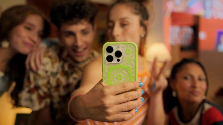 Four people taking a group selfie with a phone in an OtterBox case