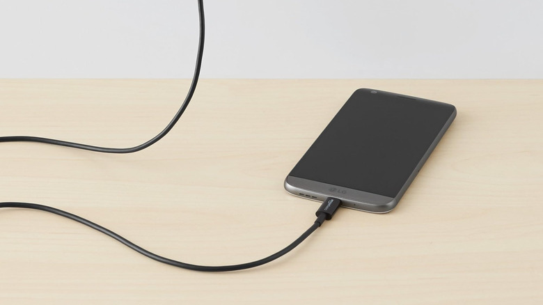 An Amazon Basics cable charging an LG phone on a wooden table
