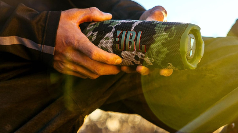 A person holding the JBL Flip 7 in an outdoor setting.