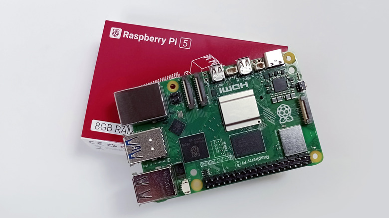 A Raspberry Pi 5 placed atop its red packaging box.