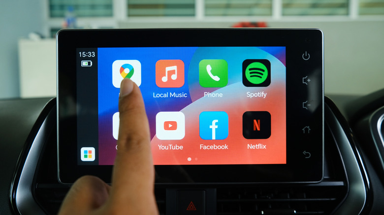 Close-up of a person touching the Google Map icon on Android Auto in a car